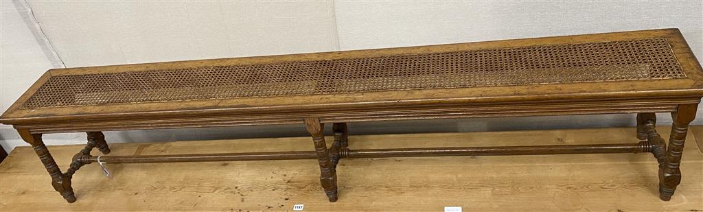 A long stool with canework seat, designed by Alfred Waterhouse for Blackmoor, Hampshire (a pair to one at Lotherton Hall), length 204cm